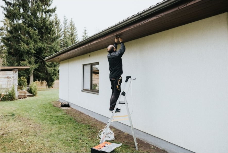 Elektriker installerer belysning på tagfoden til en villa